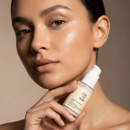 Woman holding a skincare product against a neutral background